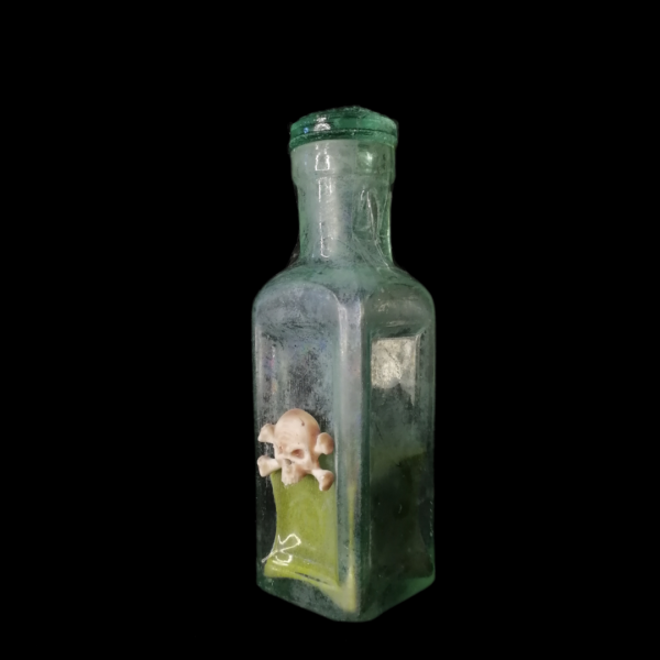 PERISHING POWDER APOTHECARY BOTTLE: A very old antique bottle, adorned with a rudimentary skull. The bottle is filled with harmless green powder and closed with its original glass lid (very unusual find).